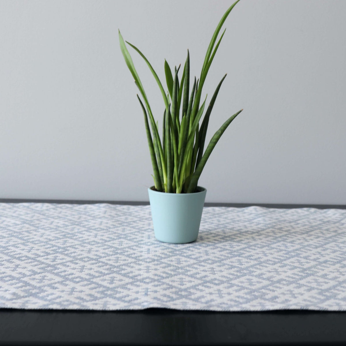 2. Close-up of Setumaa pattern table runner with potted plant, highlighting linen-cotton texture