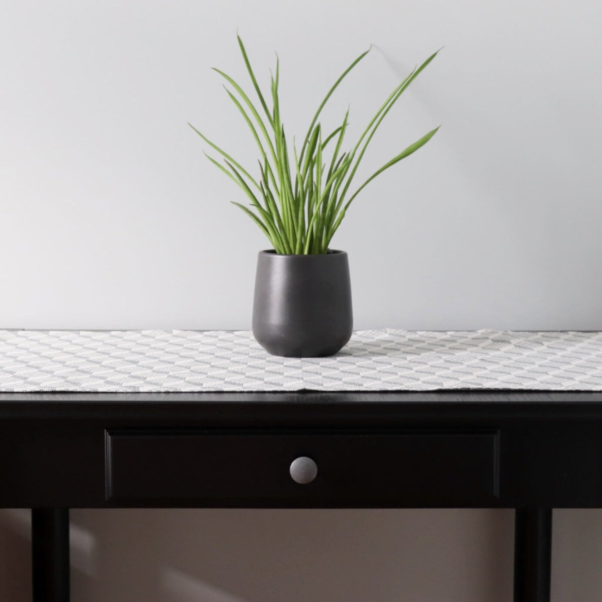 1. Table runner with Virumaa folk art pattern on dark wooden table with black plant pot