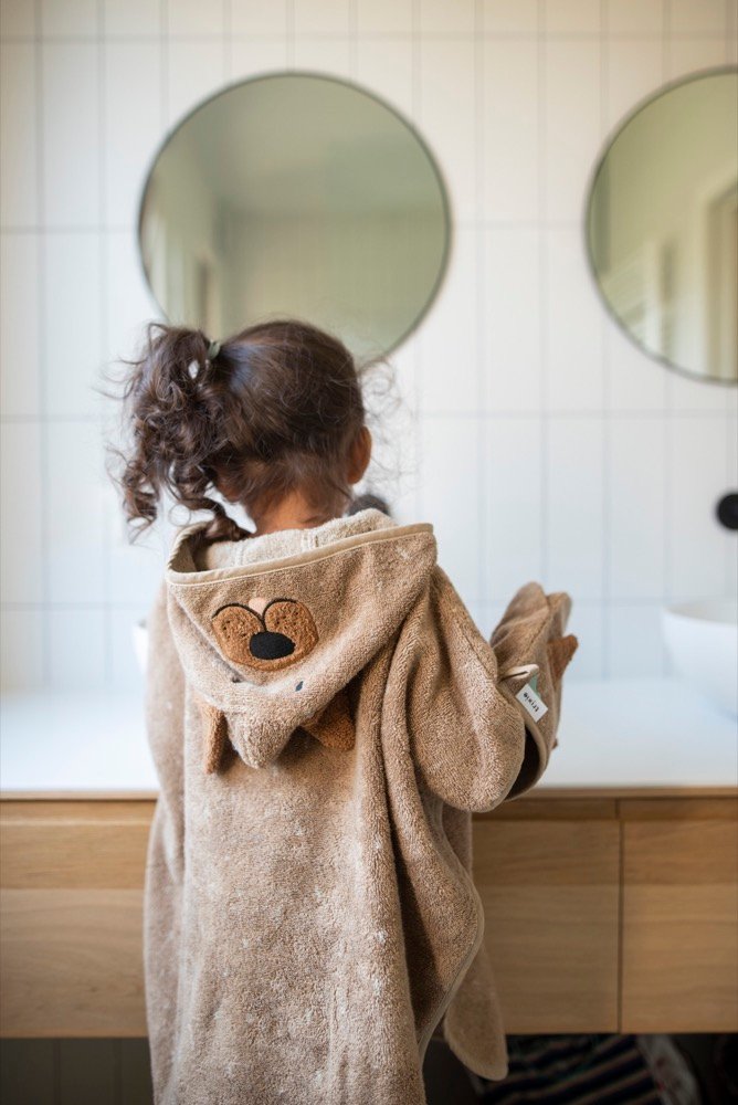 1. Child in Trixie Baby Mr. Dog hooded poncho, back view, standing at bathroom counter