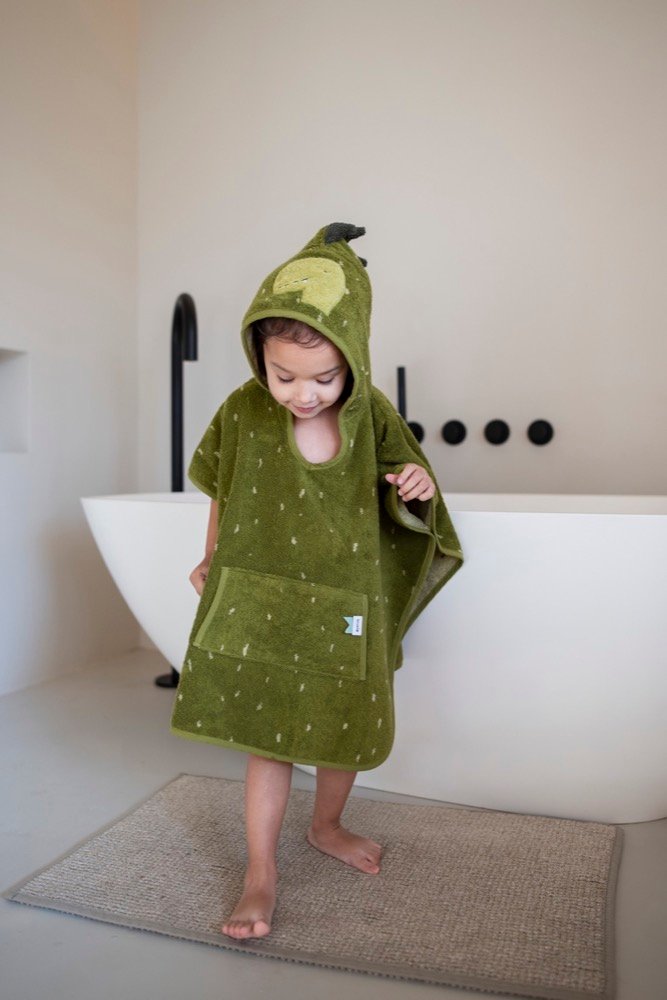 1. Child wearing green dino-themed hooded bathing poncho in bathroom setting, standing on rug near bathtub