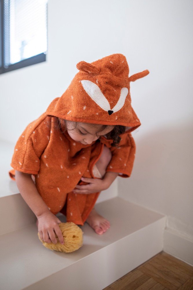 1. Child wearing orange fox-themed hooded bathing poncho sitting on stairs holding a sponge