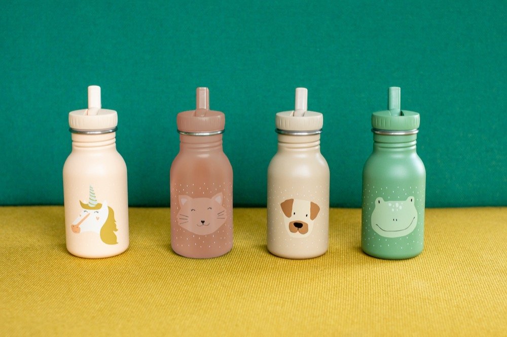 1. Four Trixie Baby stainless steel bottles with animal designs, including Mrs Cat, displayed on yellow surface with green background