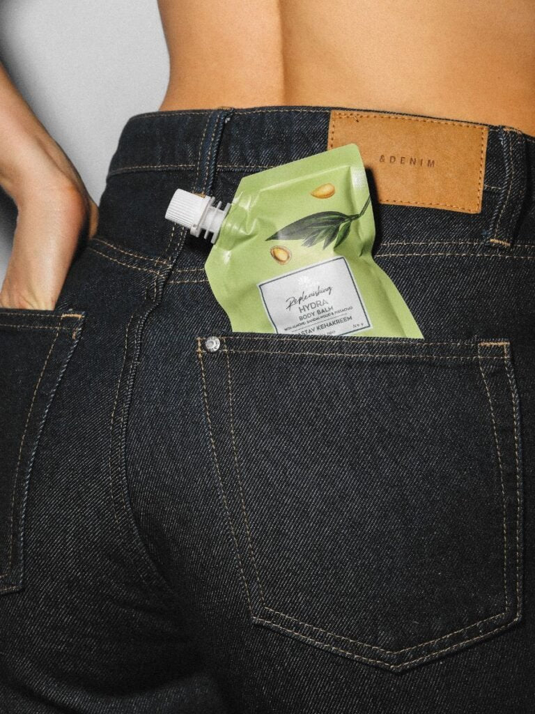 4. Magrada X Lauren Replenishing Body Balm travel size in back pocket of jeans, demonstrating compact design