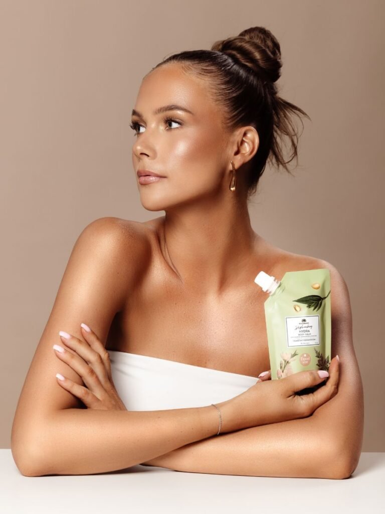 1. Woman holding Magrada X Lauren Replenishing Body Balm travel size, showcasing elegant packaging in lifestyle setting