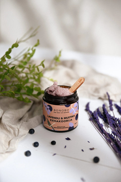3. Open jar of BONOBO Blueberry and Lavender Body Scrub with wooden spoon, surrounded by lavender and blueberries, lifestyle setting