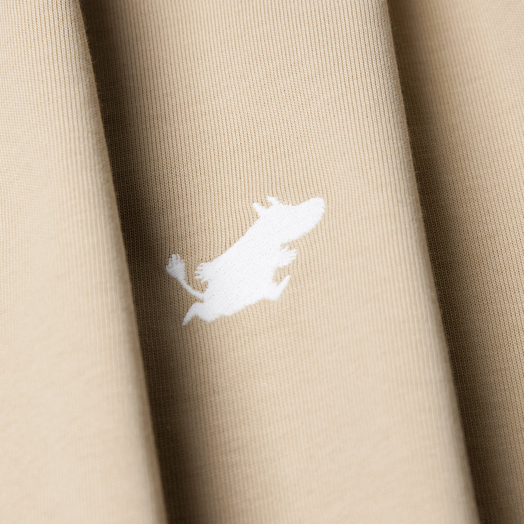 6. Close-up of white Moomin logo on beige Moomin Classics heavy t-shirt fabric