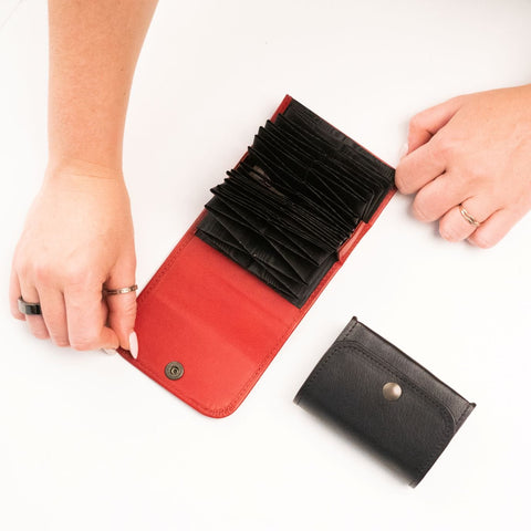 1. Papillon leather card holder in red, shown open with multiple card slots, held by a person