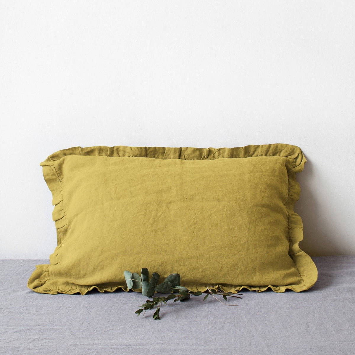 9. Yellow linen pillowcase with frills on a grey surface, adding a pop of color