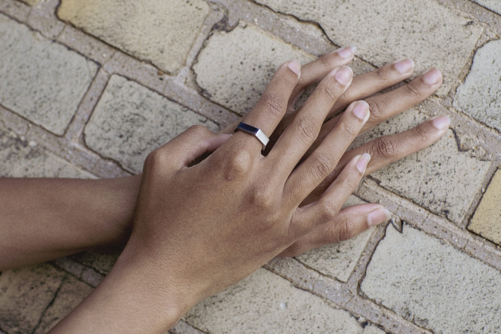 4. Woman's hands against brick wall, featuring Lentsius Plico ring in stainless steel with mixed finish