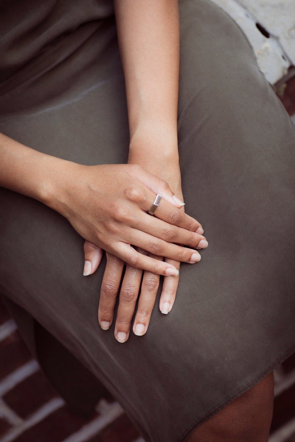 3. Woman's hands resting on lap, wearing Lentsius Plico ring in stainless steel, highlighting sustainable design