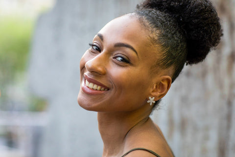1. Woman smiling while wearing Lentsius Lilac Upcycled Earrings, showcasing eco-friendly stainless steel design