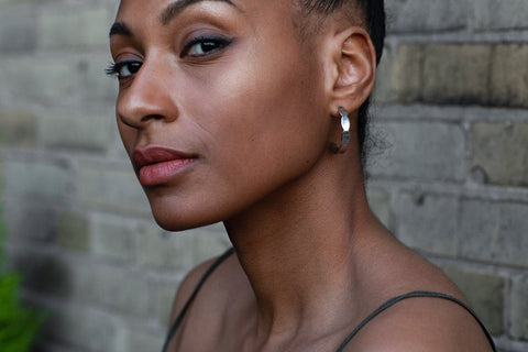 2. Close-up of woman wearing Lentsius Mare earrings against brick wall