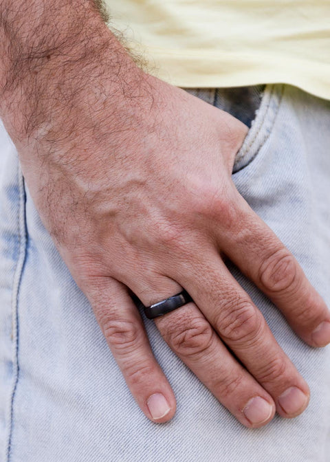 1. Man wearing Leomani black ceramic ring on left hand with casual jeans in outdoor setting