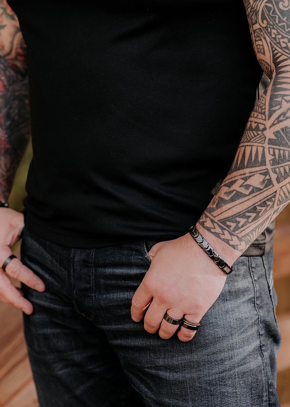 1. Man wearing Leomani black ceramic Gent bracelet with tattooed arms and black shirt in casual setting
