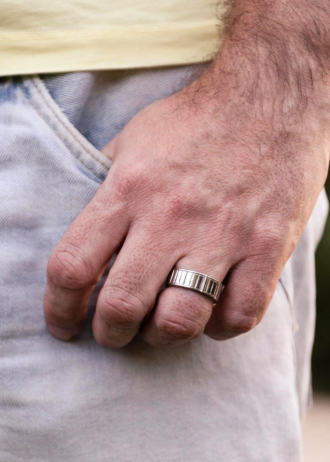 1. Man wearing Leomani Intare stainless steel ring on hand, showcasing minimalistic design and durability in casual outdoor setting