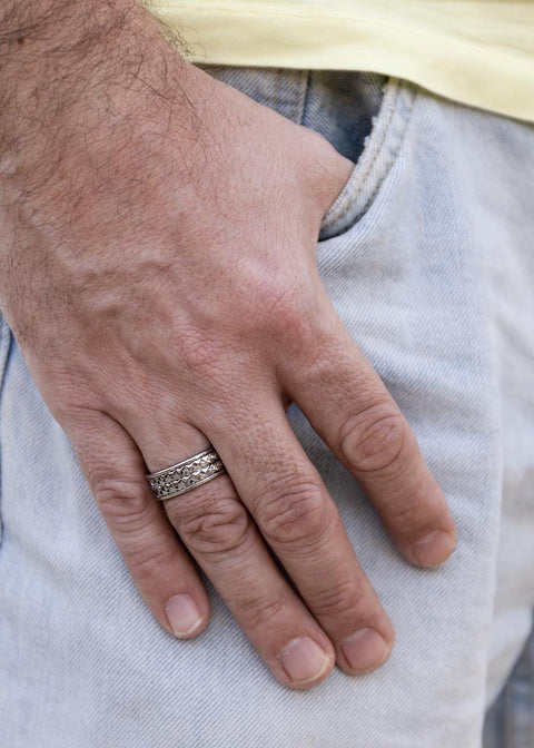 1. Man wearing Leomani stainless steel ring with braided design, hand in pocket of light denim jeans
