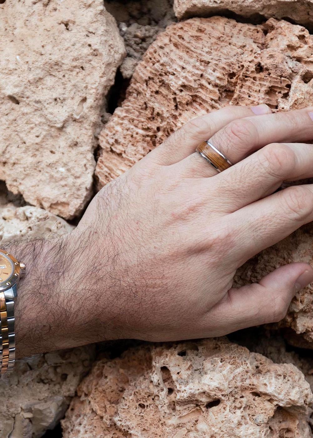 1. Man wearing Leomani Riona ring with stainless steel and natural veneer against a stone background