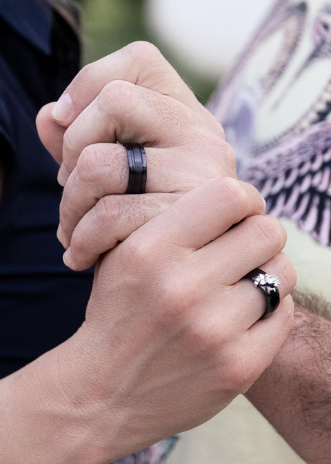 1. Couple holding hands, man wearing Leomani black ceramic ring, showcasing its elegant design in a natural setting