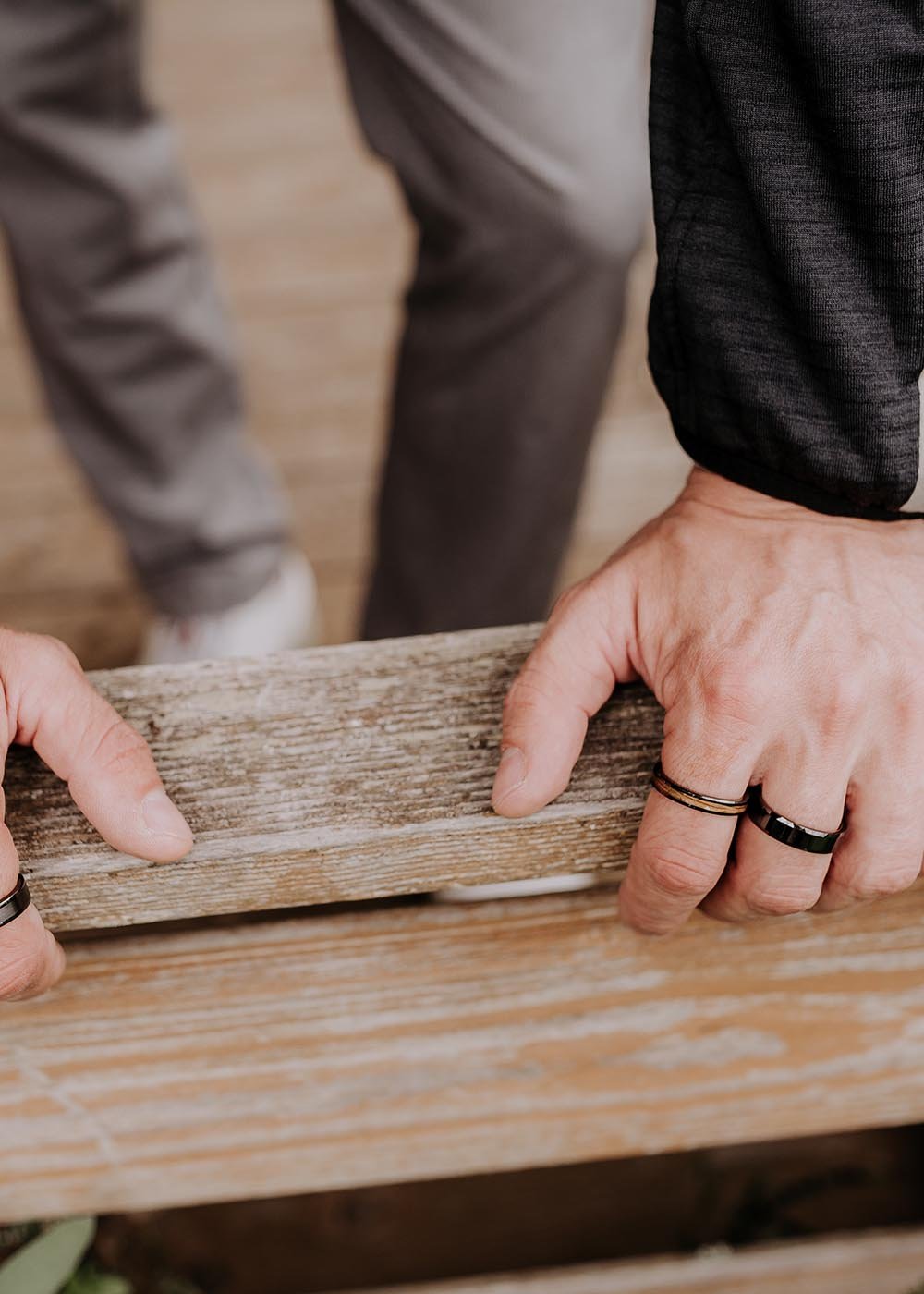 1. Two men wearing Leomani black ceramic rings with wood veneer inlay, engaged in outdoor activity on wooden deck