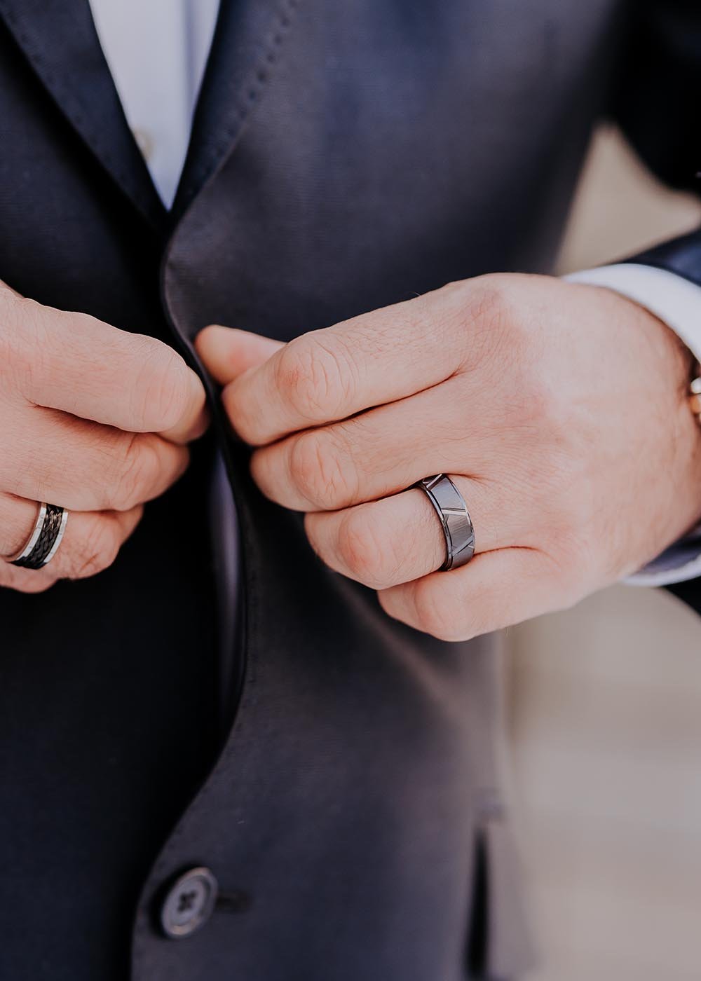 2. Close-up of man's hands adjusting suit jacket, wearing Leomani men's black ceramic ring Tau, highlighting elegant design