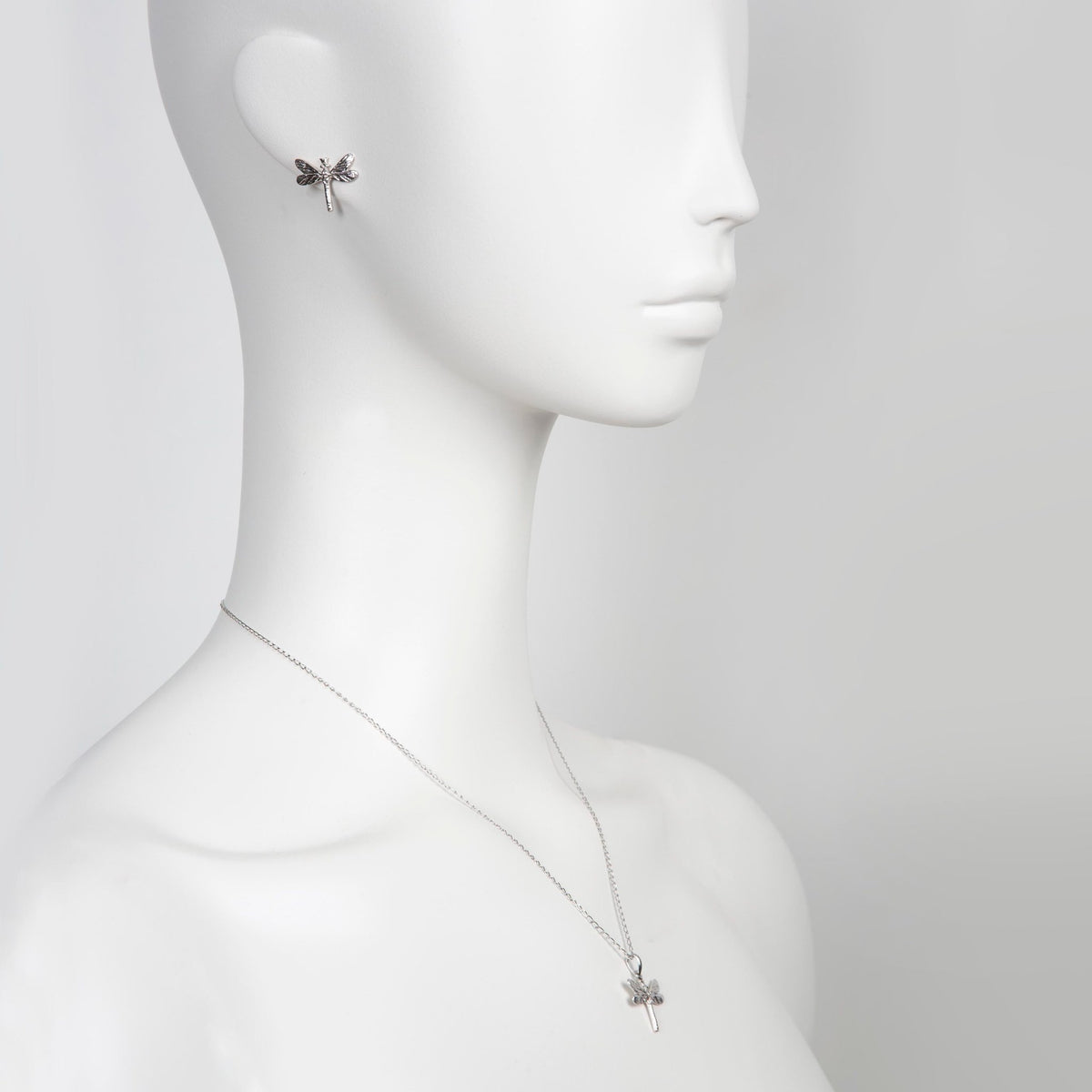 3. Mannequin wearing silver dragonfly earring and matching necklace against a plain background
