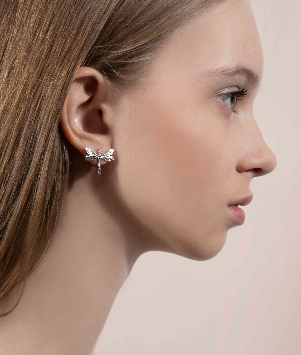 1. Woman wearing a silver dragonfly earring, side profile view highlighting the earring's detail