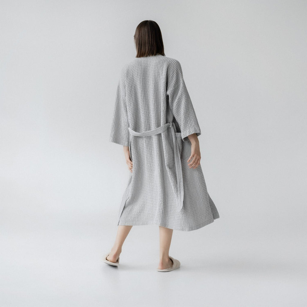 8. Woman wearing light grey honeycomb waffle bathrobe shown from back in studio