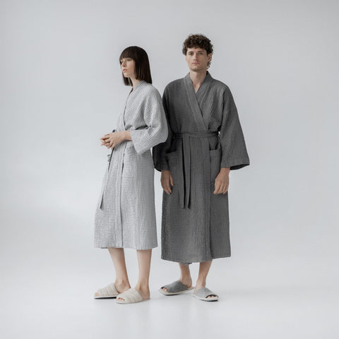 4. Man and woman wearing light grey and dark grey bathrobes standing side by side in studio