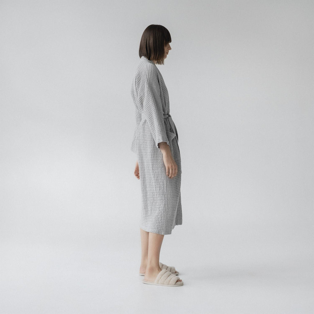 7. Woman wearing light grey honeycomb waffle bathrobe shown from side in studio