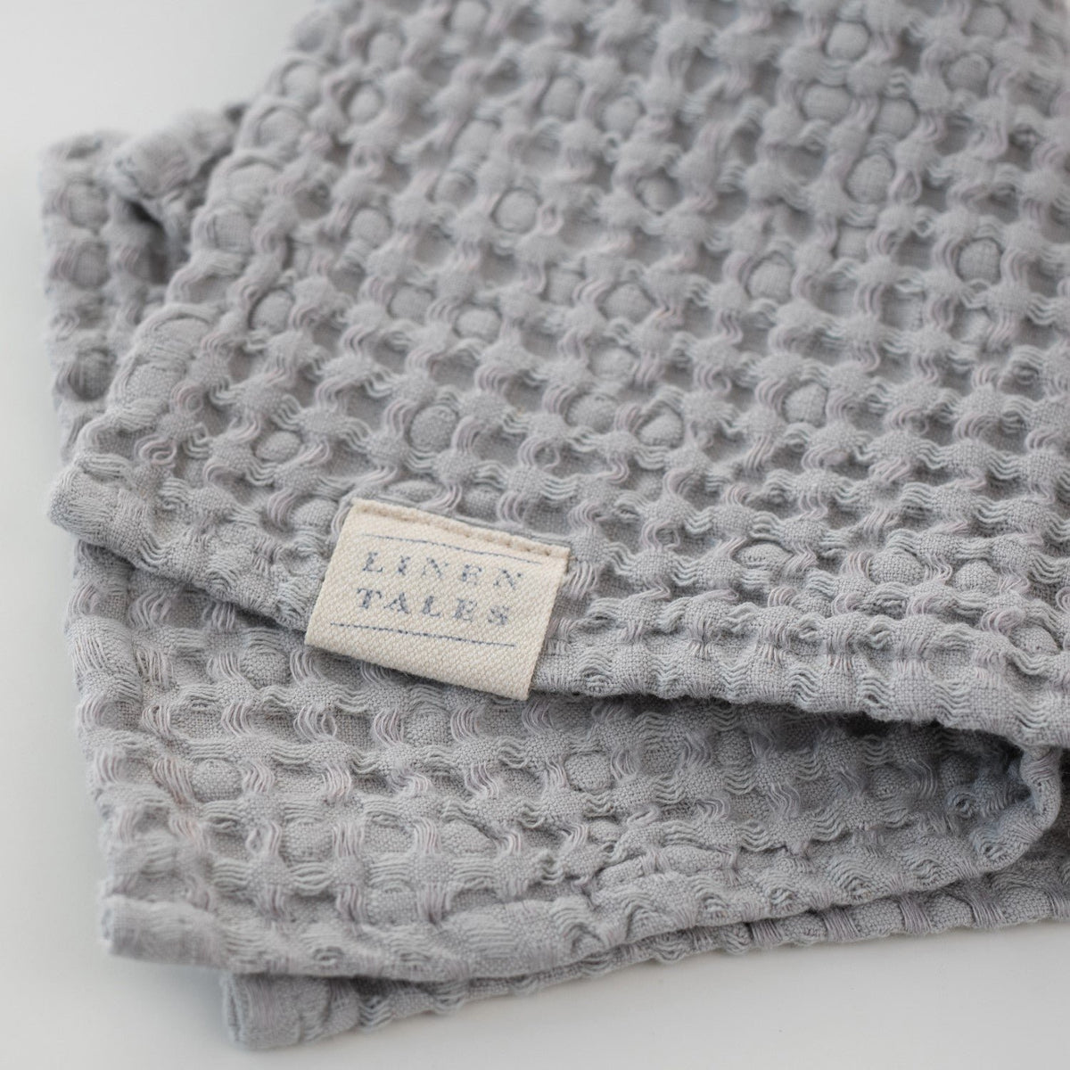 4. Light grey honeycomb waffle towel with Linen Tales label, highlighting brand and texture