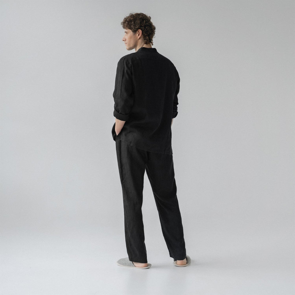 3. Man shown from back wearing black linen loungewear set with hands in pockets in a studio setting