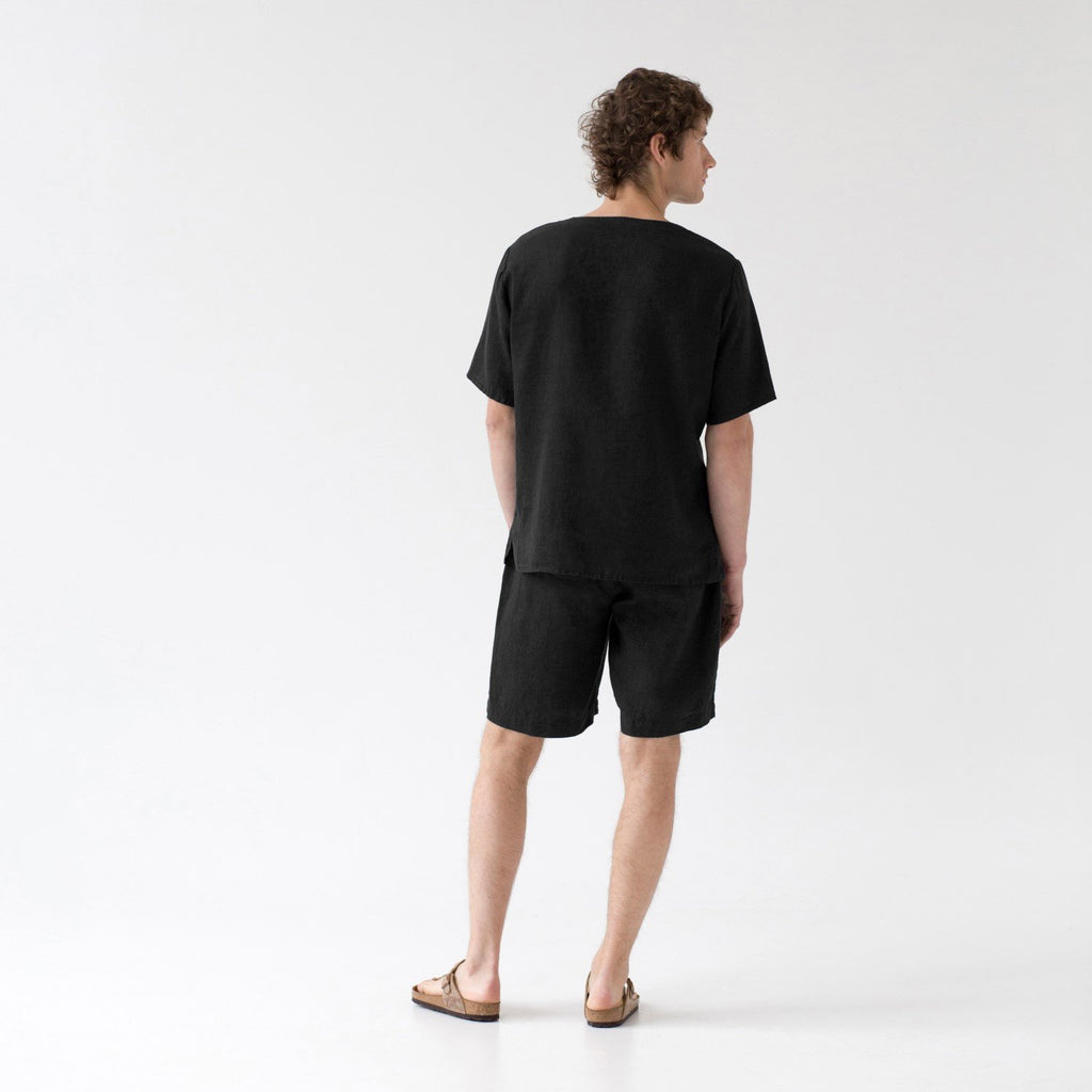 2. Back view of man in black linen pyjama set with relaxed fit, in a studio setting