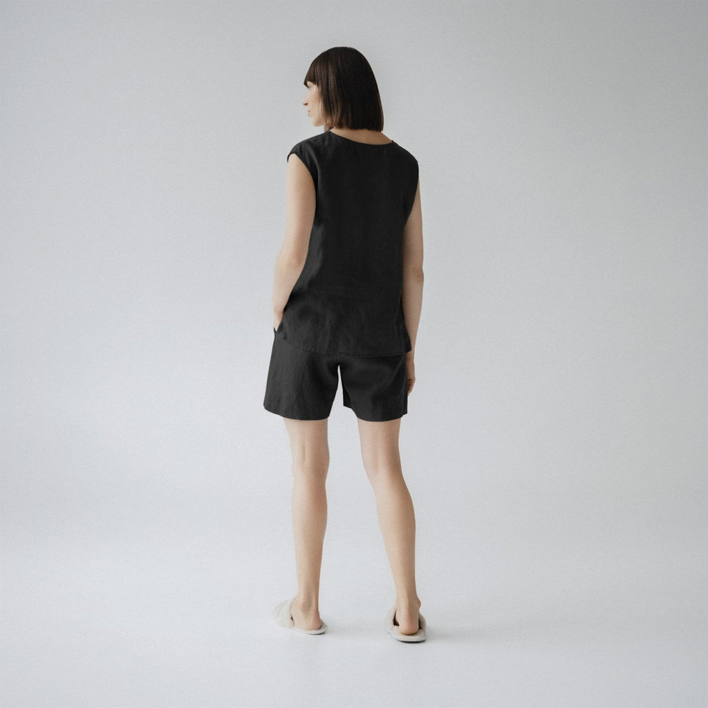 2. Woman shown from back wearing black linen pyjama set with sleeveless top and shorts, in a studio setting