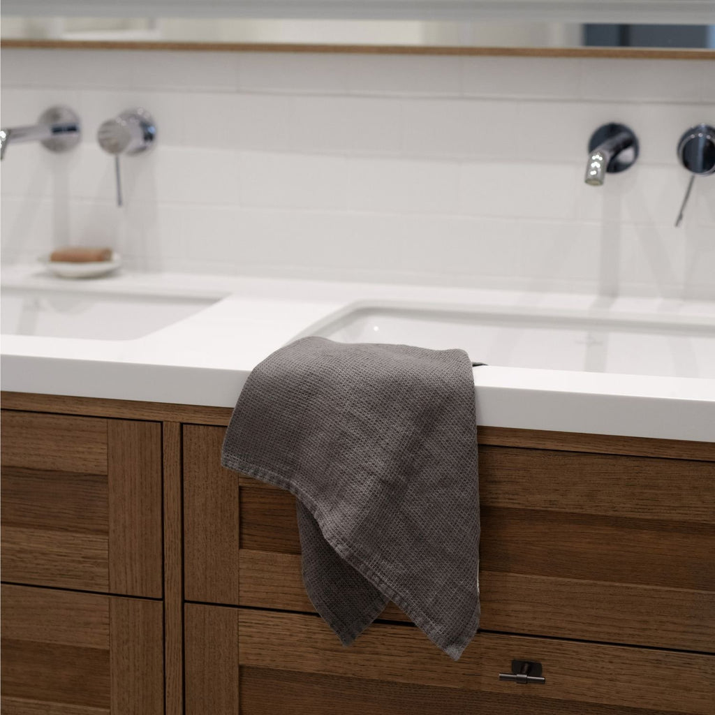 5. Charcoal waffle linen towel draped over a wooden bathroom sink, modern interior design
