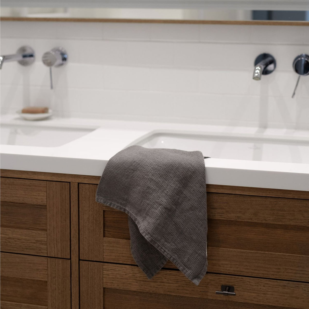 5. Charcoal waffle linen towel draped over a wooden bathroom sink, modern interior design
