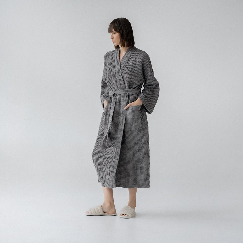 9. Woman wearing dark grey honeycomb waffle bathrobe with hands in pockets in studio
