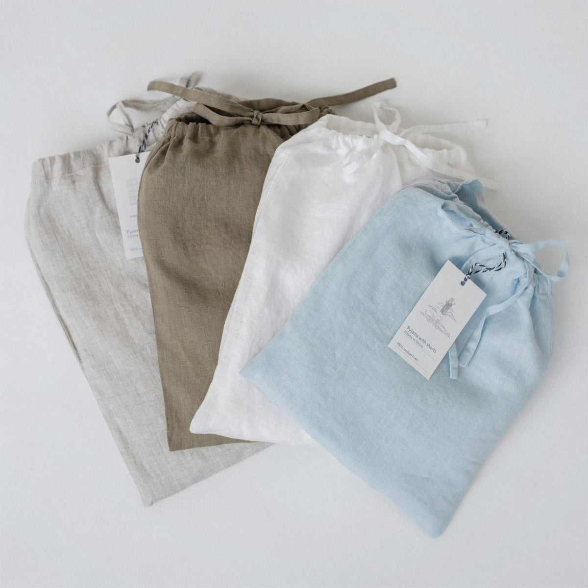 5. Four linen bags in beige, brown, white, and blue with drawstrings and tags, laid flat