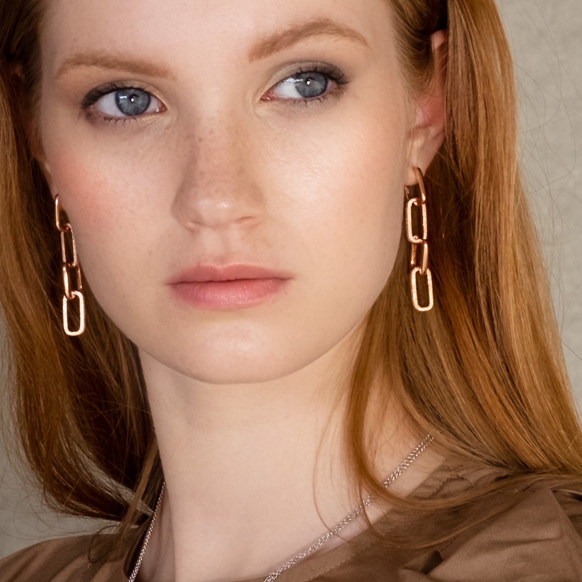 1. Woman wearing MyaMoon Metropolitan Longing Earrings in rose gold, showcasing Nordic minimalism and elegance