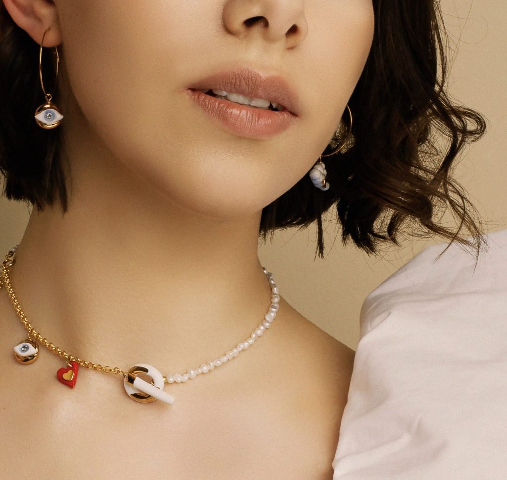 3. Woman wearing SCULP Eye in the Sky earrings and matching necklace, highlighting ceramic and gold details, lifestyle image