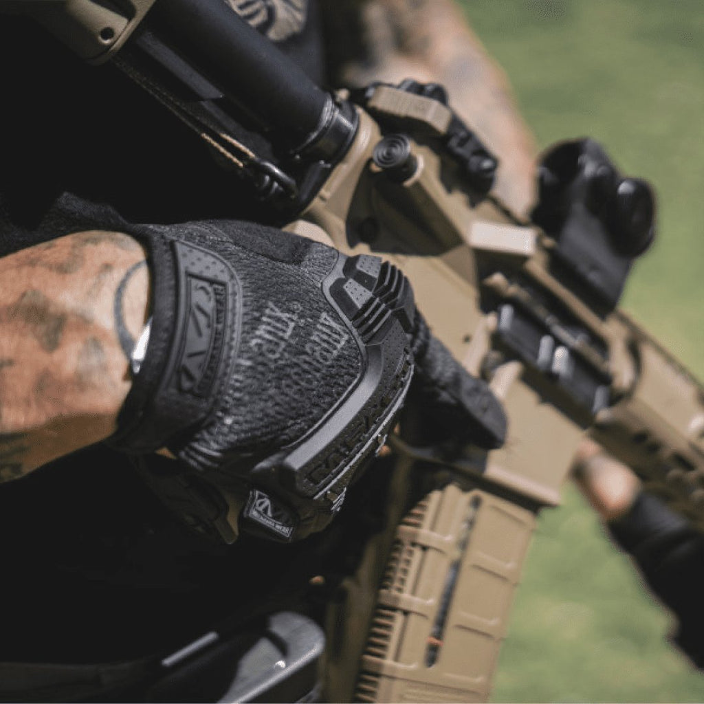 1. Person wearing black Mechanix M-Pact glove holding a rifle outdoors