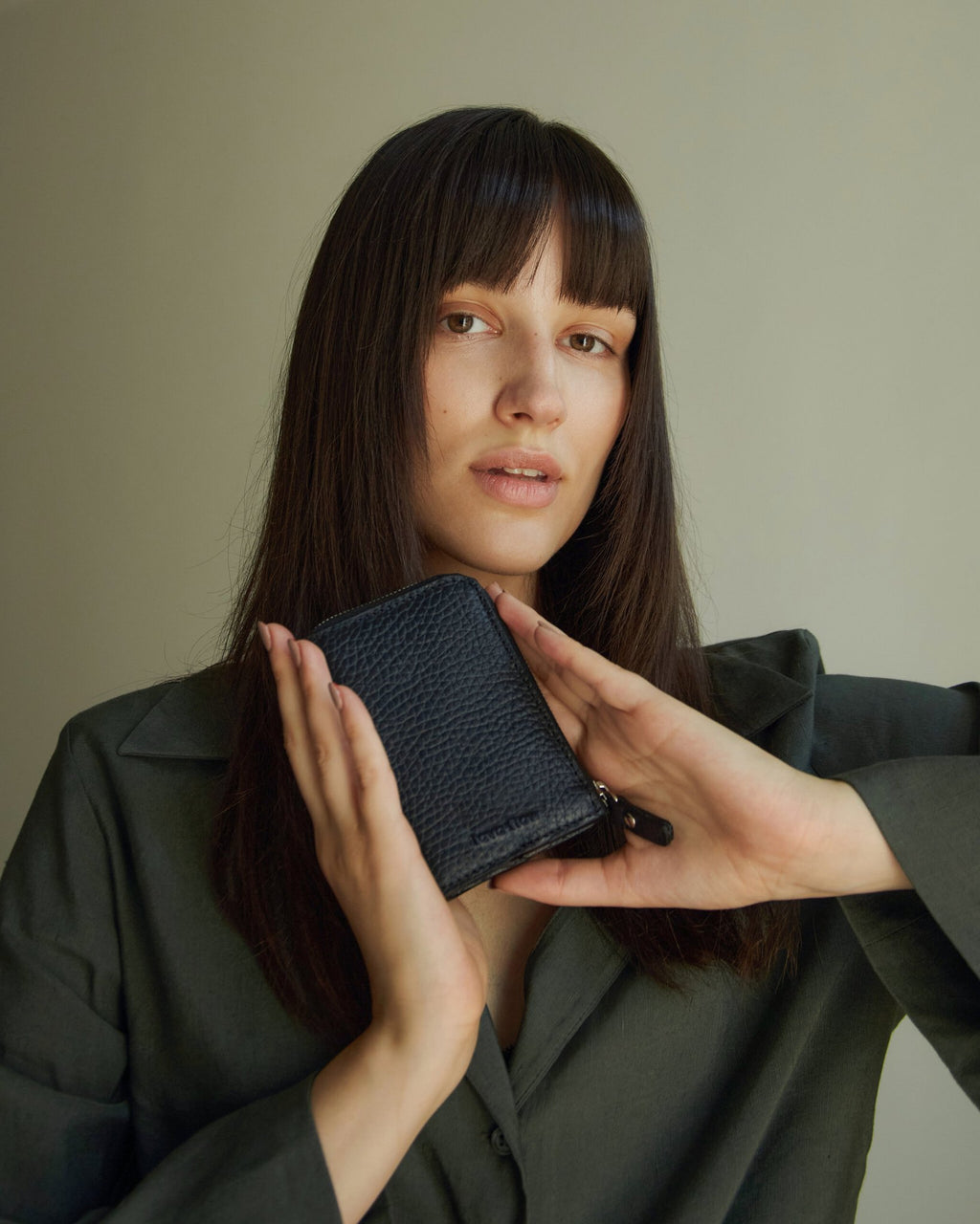 1. Woman holding Lava Flow Classic Leather Wallet MACA in black, showcasing compact design and texture