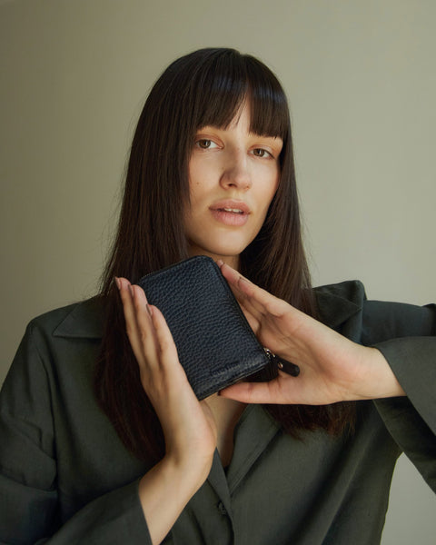 1. Woman holding Lava Flow Classic Leather Wallet MACA in black, showcasing compact design and texture
