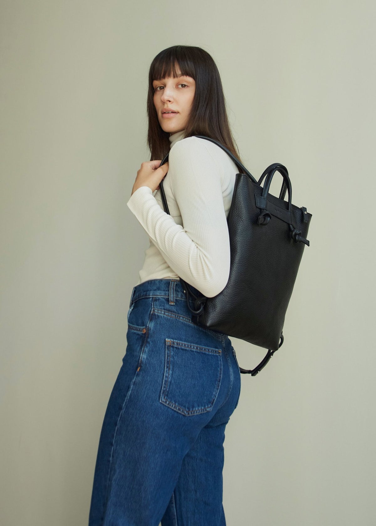 5. Woman wearing Lava Flow ALICE ARM black leather backpack, demonstrating fit and style