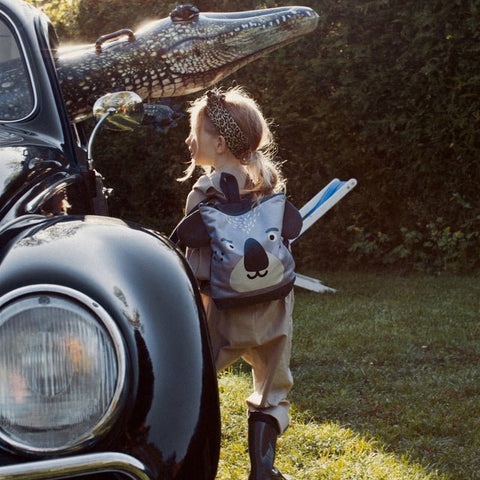 2. Child with Muni Koala backpack near vintage car, highlighting outdoor adventure setting