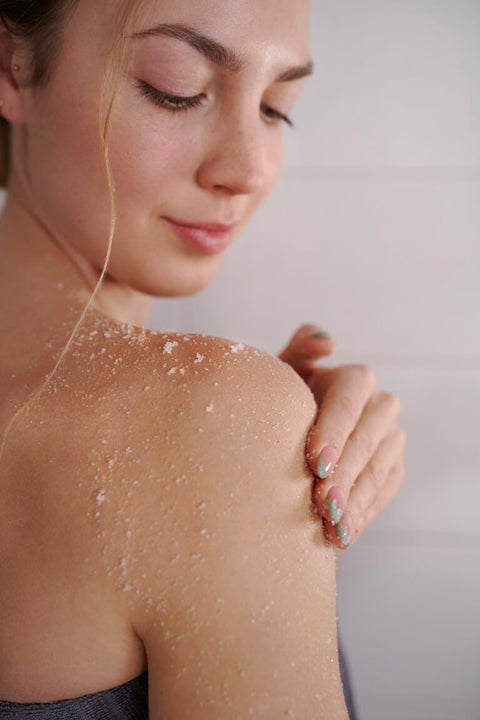 2. Woman holding Magrada Sleep&Glow body oil in bed, showcasing product use