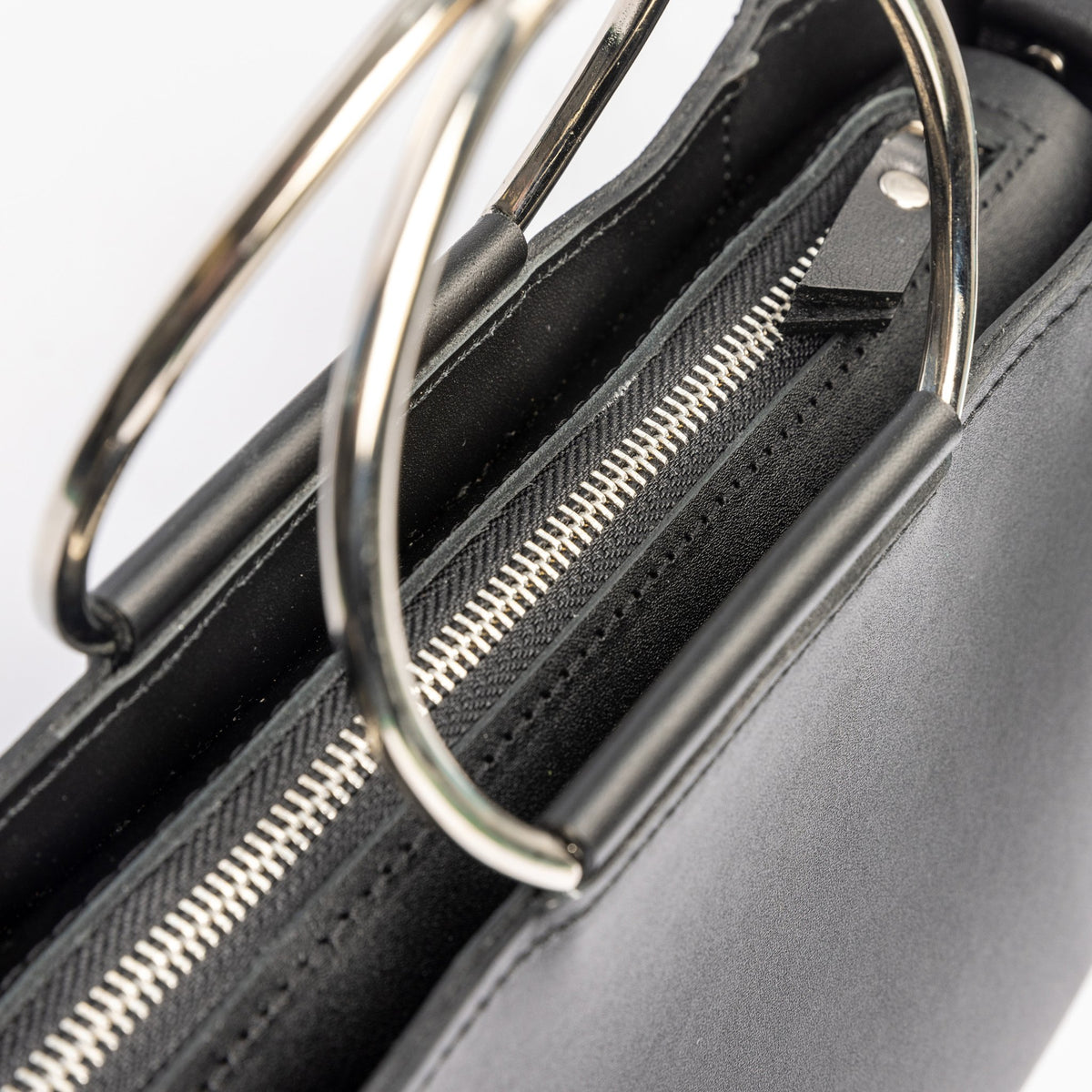 6. Close-up of zipper and metal handles on PYKOK Handbag Maria Mini in black leather