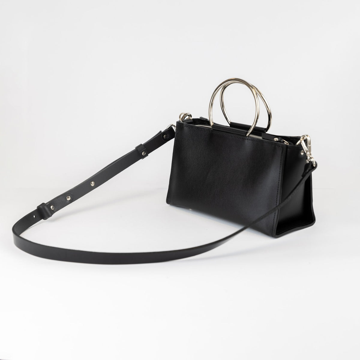 1. PYKOK Handbag Maria Mini in black leather with adjustable strap, shown in studio setting