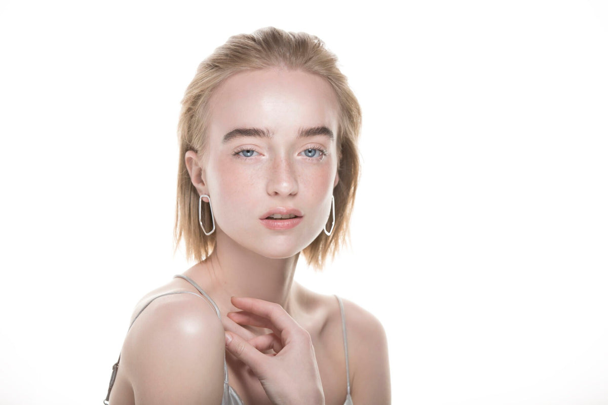 1. Woman wearing Lisa Kroeber Jewellery Frames Silver Earrings in studio setting