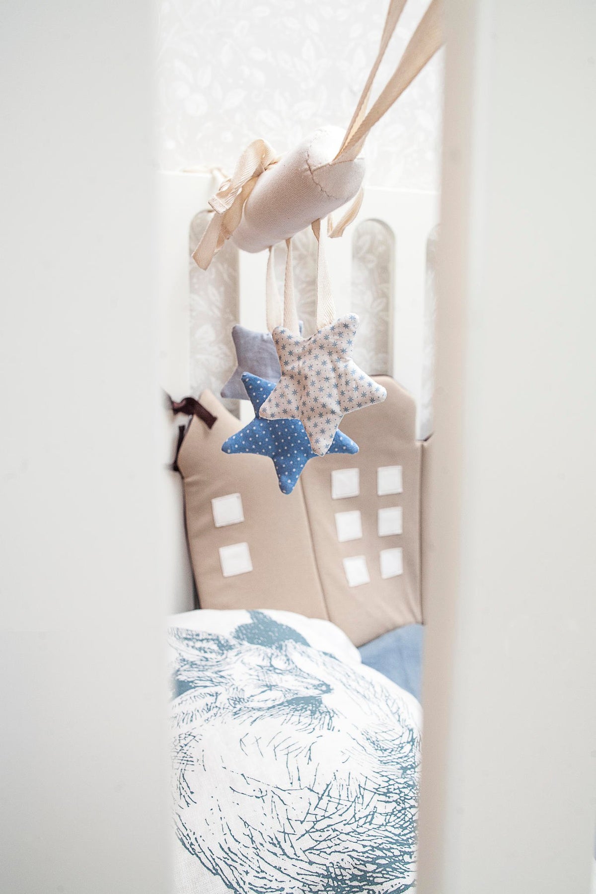 1. Blue star-shaped baby crib toy hanging in a crib, enhancing fine motor skills and auditory development with crinkle and ring sounds.
