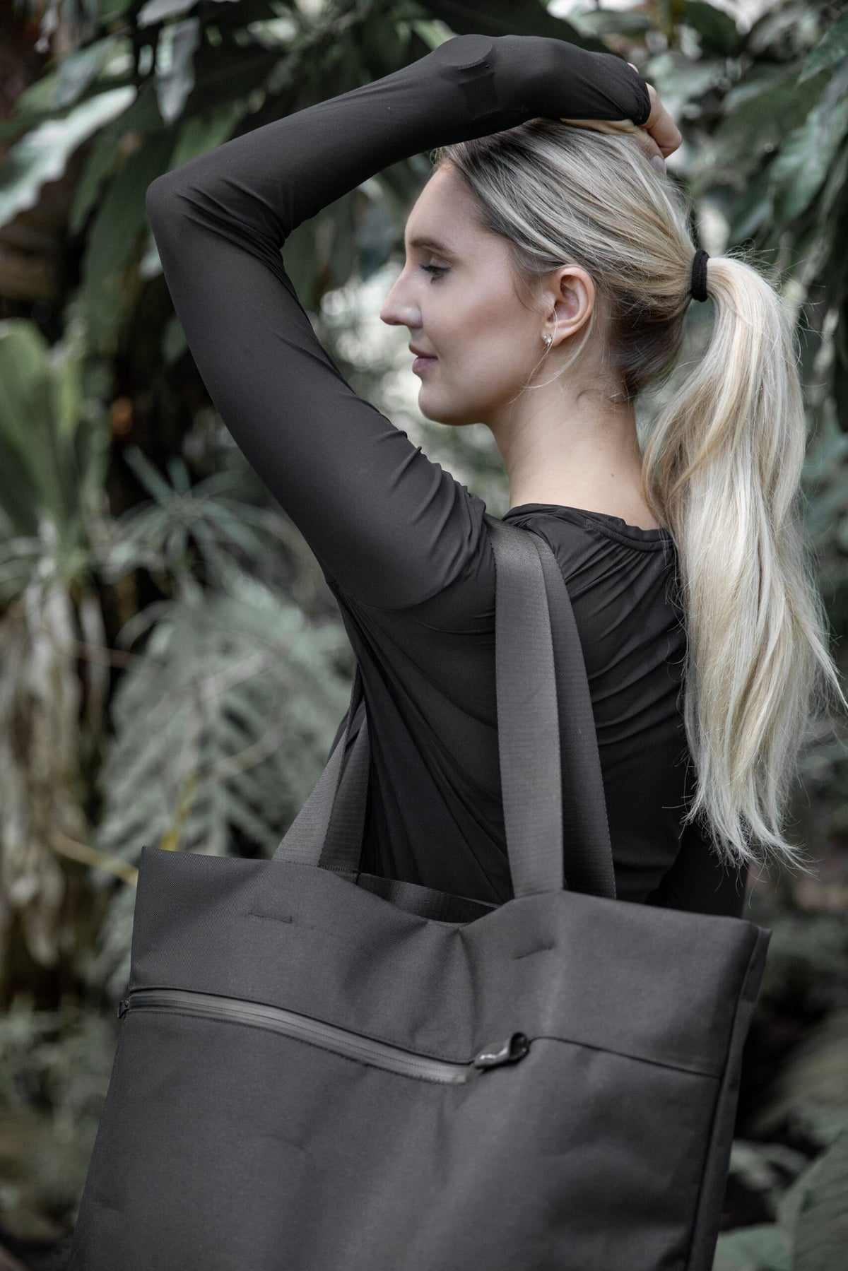 7. Woman with Nordhale VIK Tote Bag in black, emphasizing its spaciousness and style in a natural setting